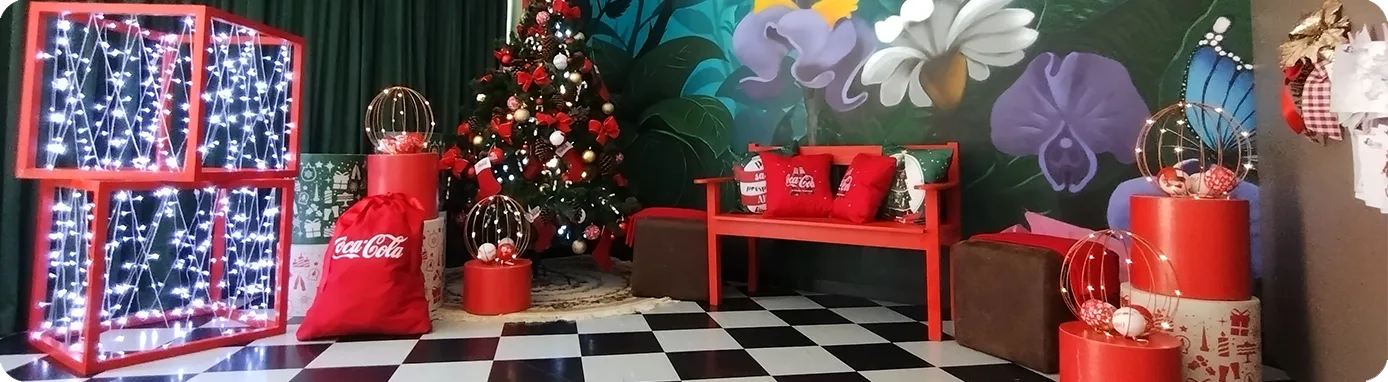 Cenografia de Natal da Coca-Cola com árvore, luzes e mobiliário da marca
