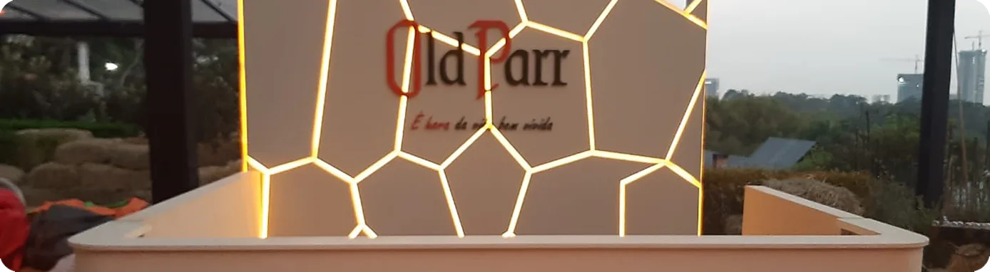 Balcão da Old Parr com painel iluminado em favo, instalado em evento ao ar livre