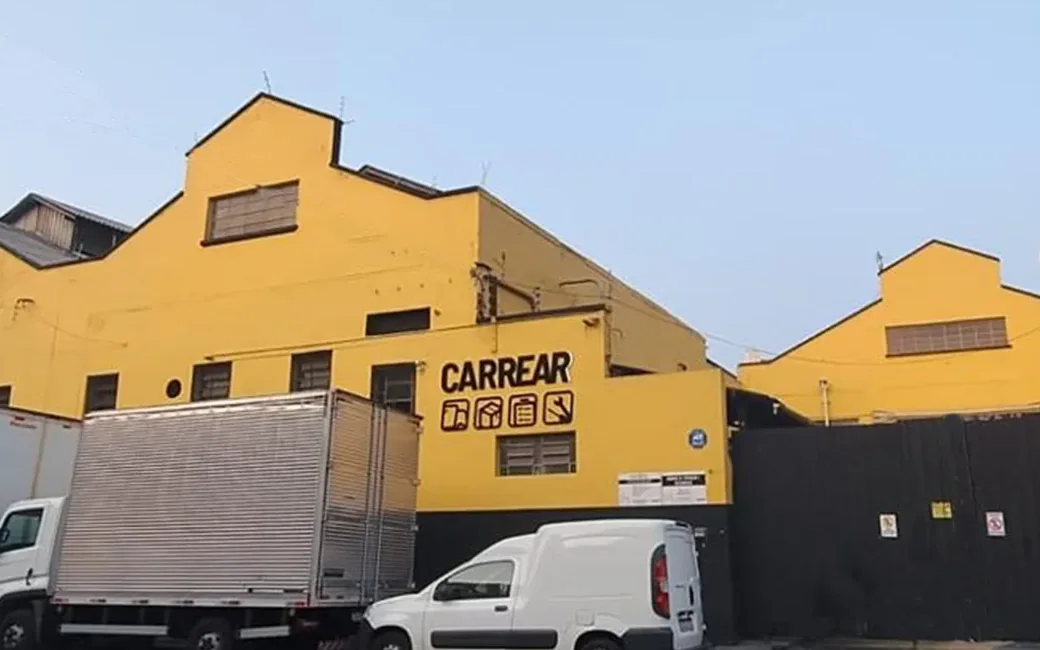 Fachada amarela do galpão da Carrear na Mooca, em São Paulo, com a frota estacionada em frente